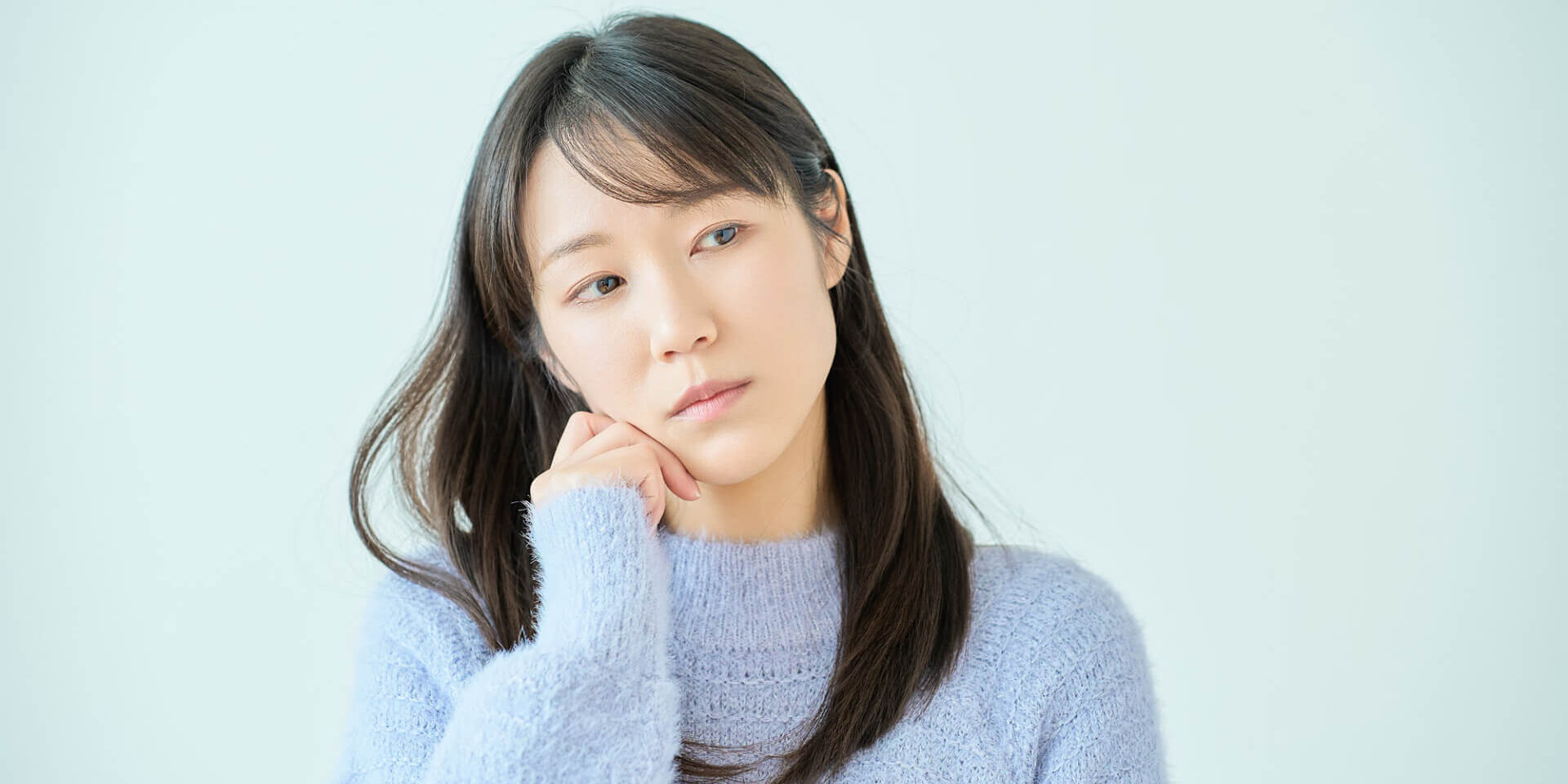 右手を頬にあてて考える女性